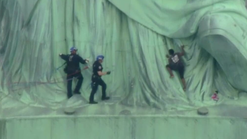 Illustration for article titled A Black Woman in Handcuffs For Climbing The Statue of Liberty on Independence Day is a Perfect Metaphor For America
